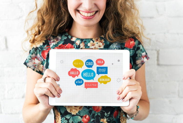 femme qui porte une pancarte avec bonjour écrit en plusieurs langues